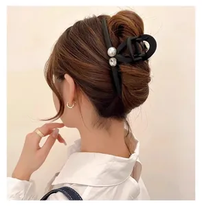 Vue arrière élégante pince à cheveux noire mate avec perle et strass sur chignon