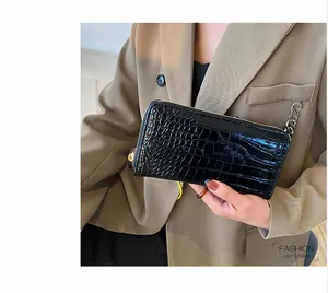 Detalle de una cartera larga de moda en cuero sintético negro con relieve de cocodrilo