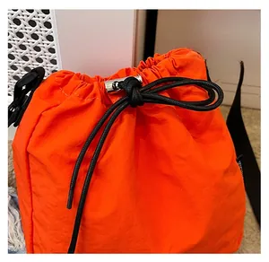 Close-up of durable drawstring closure and toggle detail on bright orange nylon bucket bag