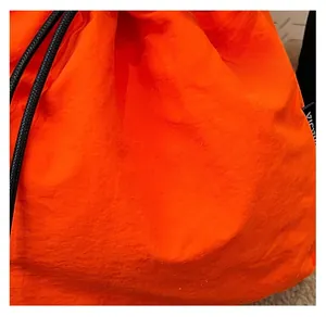 Close-up detail of high-quality bright orange nylon fabric on a sports drawstring bag