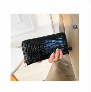 Vista detallada de una elegante cartera de mano negra con motivo de cocodrilo en mano