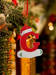 Vista dettagliata di un addobbo natalizio a forma di lettera G rossa con cappello di Babbo Natale.