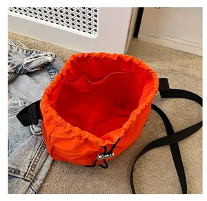 Close-up of the spacious interior and inner pocket of an orange nylon bucket bag.