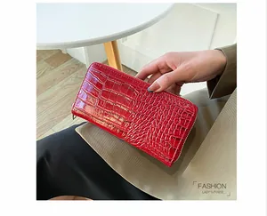 Primer plano detallado de una cartera de mano larga roja brillante con textura de cocodrilo