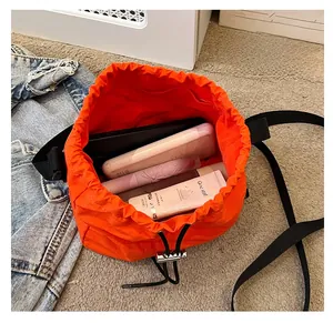 Inside view of orange nylon drawstring bucket bag showing large capacity for cosmetics