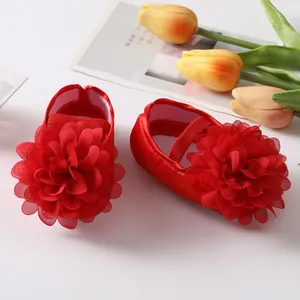 Vue détaillée de chaussures de princesse rouges pour bébé avec grandes fleurs en tissu.