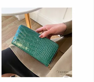 Detalle de una cartera larga de mujer verde con estampado de cocodrillo y cremallera
