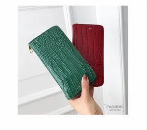 Primer plano de carteras largas de mujer en cuero PU con relieve de cocodrilo verde y rojo