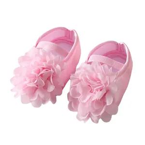 Chaussures de princesse roses pour bébé avec grandes fleurs décoratives sur fond blanc