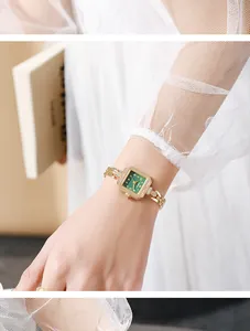 Close-up detail of a vintage square quartz watch with a green dial and gold chain bracelet