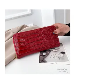 Detalle de una cartera larga para mujer en color rojo con relieve de piel de cocodrilo