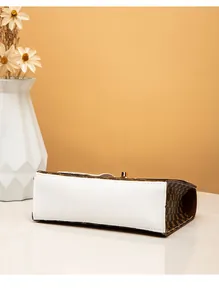 Detailed side view of a stylish white and brown monogram patterned small square handbag