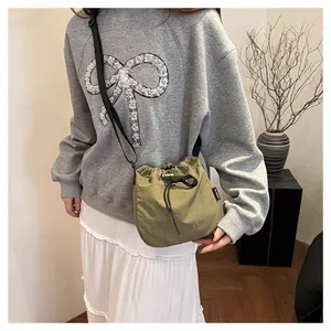 Detail of lightweight olive nylon drawstring bucket bag worn with casual outfit