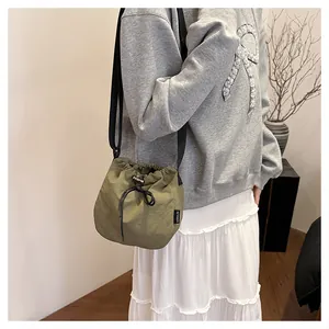 Lifestyle view of a lightweight olive green nylon drawstring bucket bag for women