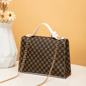 Elegant women's vintage clover print handbag with gold chain strap and white handle.
