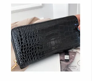 Detalle macro de una cartera de mano larga para mujer en cuero PU negro con cocodrilo