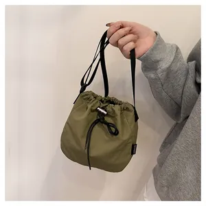 Detailed view of a green nylon drawstring bucket bag with a black crossbody strap