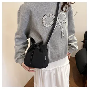 Lifestyle detail view of a lightweight black nylon bucket bag featuring a secure drawstring closure