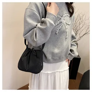 Fashionable black nylon drawstring bucket bag shown as a crossbody bag on a female model