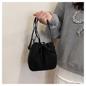 Detailed view of a black nylon drawstring bucket bag being held by a model