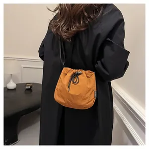 Close-up of a stylish orange nylon drawstring bucket bag worn over a black coat
