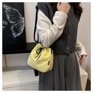 Close-up of a stylish yellow nylon drawstring bucket bag worn by a model in casual outfit