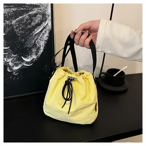 Close-up detail of a bright yellow nylon drawstring bucket bag held by a hand