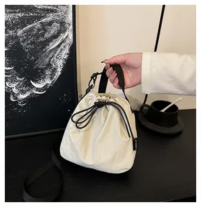 Hand-held close-up of a lightweight cream nylon drawstring bucket bag in a cafe setting