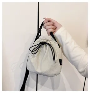 Close-up detail view of a lightweight nylon drawstring bucket bag held by a hand model