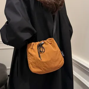 Fashionable orange nylon drawstring bucket bag with black strap for casual everyday wear