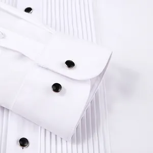 Close-up of a white formal tuxedo shirt featuring pleated front and black cuff studs.