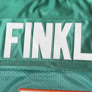 Detailansicht der weißen 'FINKL' Stickerei auf dem türkisfarbenen American Football-Trikot
