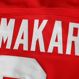 Detailed view of high-quality white embroidered lettering on a red hockey jersey fabric
