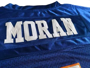 Makro-Detail des weiß gestickten MORAN-Namens auf einem blauen Football-Trikot aus Mesh