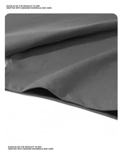 Close-up of double-stitched hem on a heavyweight grey cotton T-shirt showing fabric texture.