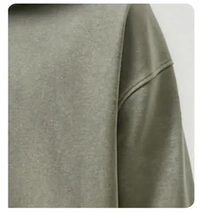 Vue rapprochée de la texture du tissu délavé et vieilli sur l'épaule d'un sweat à capuche olive