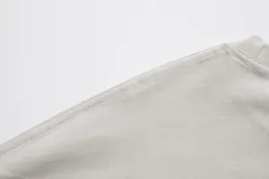 Macro detail of high-quality triple-needle stitching on a drop shoulder beige cotton tee