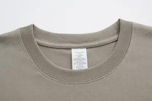 Close-up detail of the crew neckline and cotton wash care label on a beige T-shirt