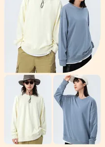 Couple wearing oversized drop shoulder crewneck sweatshirts in light blue and cream colors.