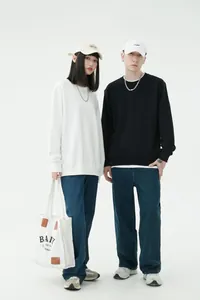 Una coppia che indossa felpe girocollo a spalla scesa bianche e nere in stile streetwear.