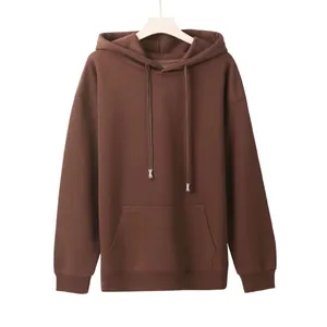 Detailed view of a brown oversized hoodie with drawstring aglets and a kangaroo pocket.