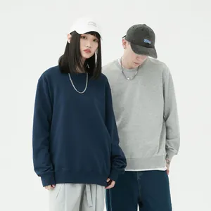 Coppia che indossa felpe girocollo oversize blu navy e grigie in uno studio bianco minimal.
