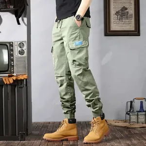 Side profile of olive green cargo joggers featuring multiple pockets and elastic cuffs