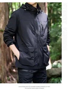 Detailed view of men's black windproof hooded jacket in an outdoor forest setting