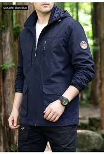Close-up detail of navy blue windproof outdoor jacket for men in a lush forest setting