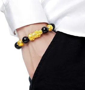 Detailed view of a gold Pixiu wealth bracelet with black obsidian beads on a man's wrist.