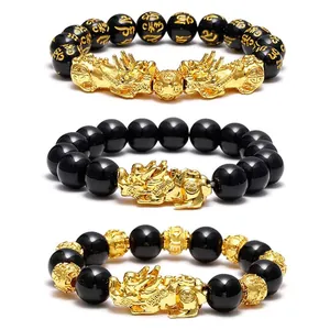 Detail view of black obsidian bracelets with gold Pixiu charms and mantra beads.