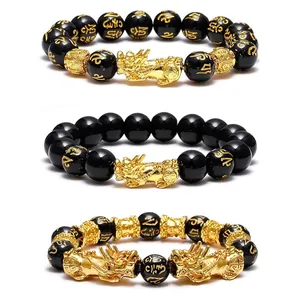Detail view of black obsidian bracelets featuring gold Pixiu charms and mantras.
