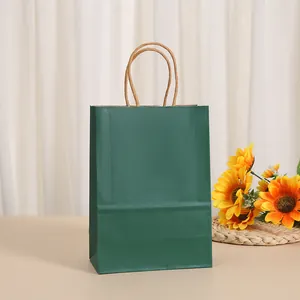 Detail of a dark green kraft paper gift bag with twisted rope handles in a warm setting.