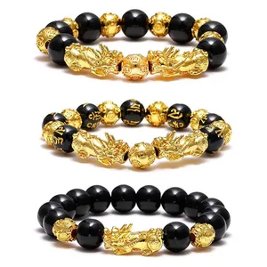 Close-up view of three distinct obsidian Pi Xiu bracelets featuring gold mantra beads